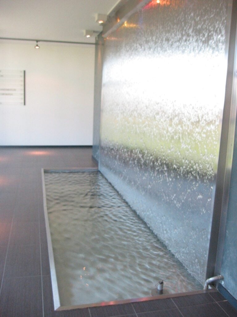 Mur d'eau en inox brossé avec bassin, réalisation sur mesure pour un hall
