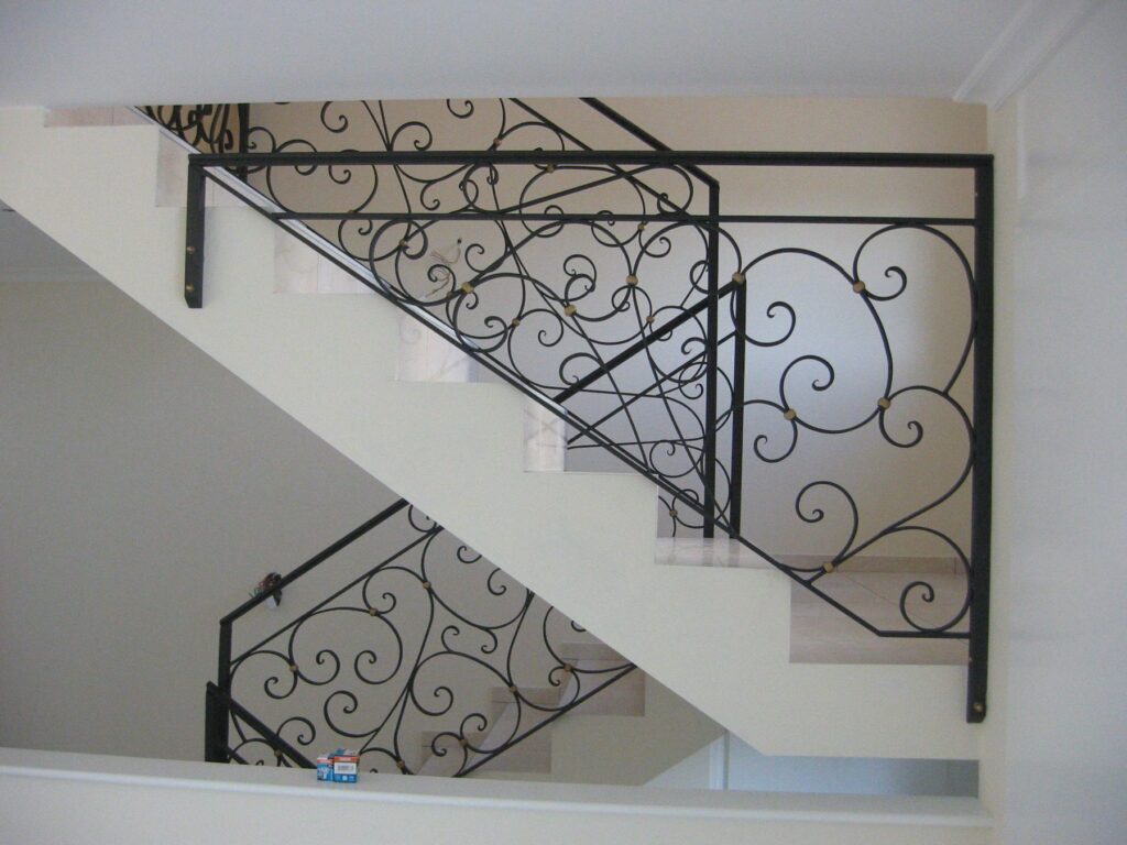 Rampe en fer forgé à volutes le long d'un escalier intérieur blanc