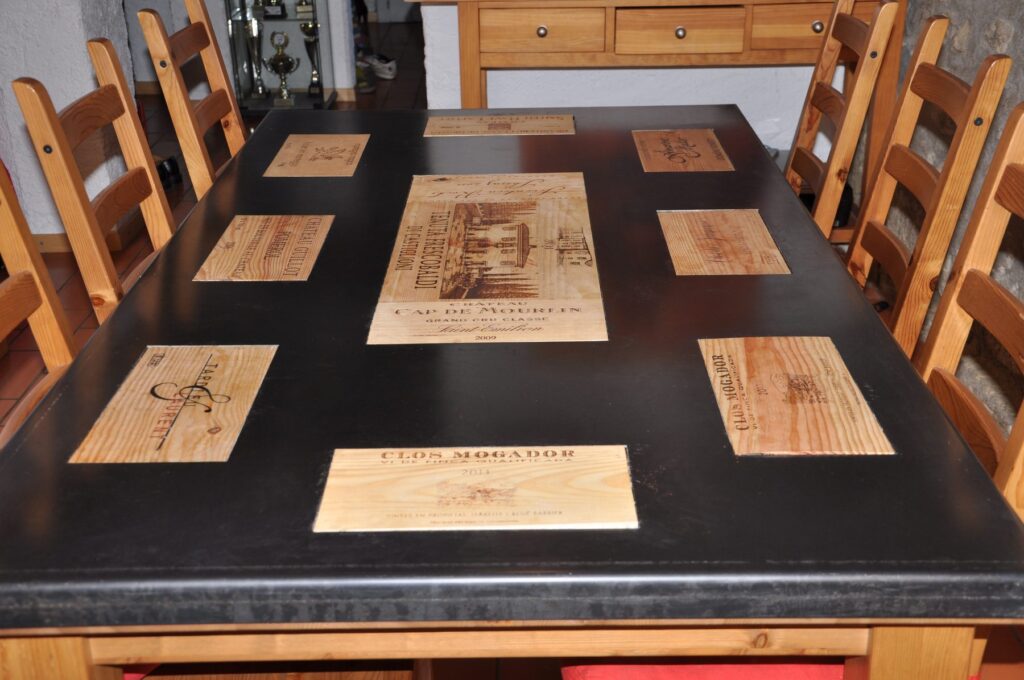 Grande table noire incrustée d'étiquettes de caisses de vin